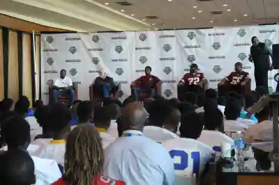 Football players speak to a crowd